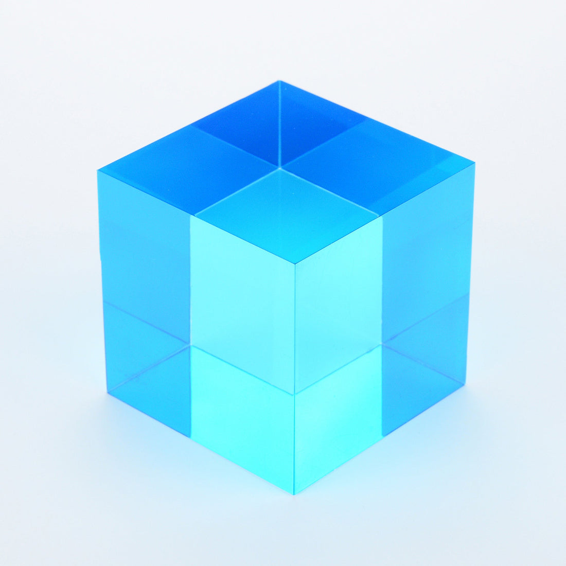A single cyan translucent cube on a white surface, one of the three subtractive primary colours